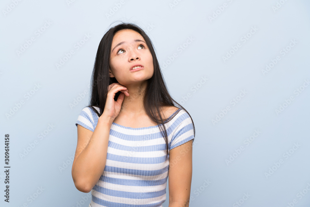 Teenager asian girl over isolated blue background thinking an idea Teenager asian girl over isolated blue background thinking an idea
