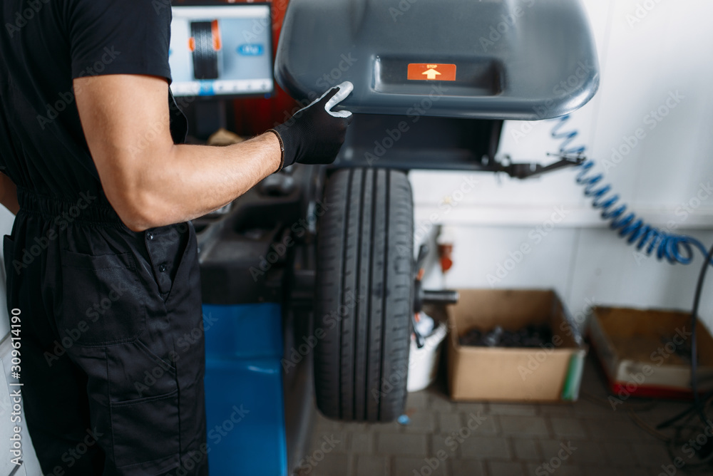 Fototapeta premium Mechanic fixing wheel on the balancing machine