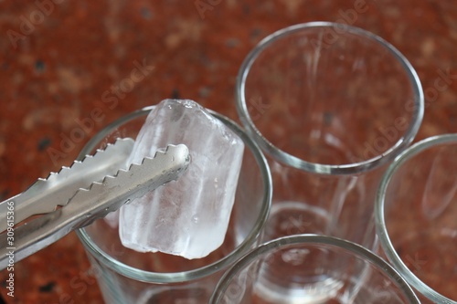 Ice cube on tongs to put in a glass
