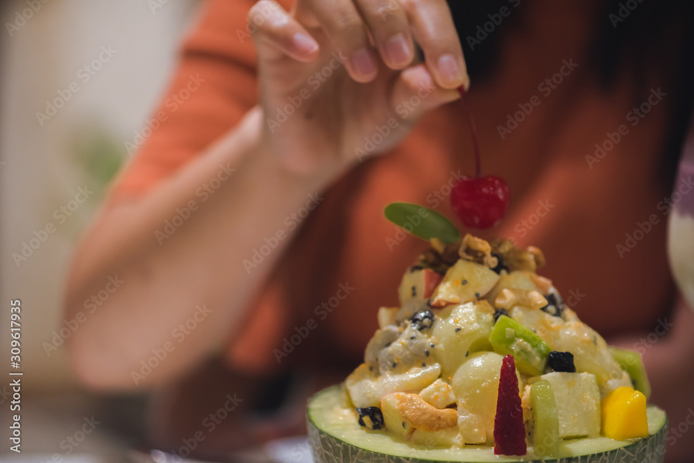 The hand of the girl picking fruit salad in a restaurant,Healthy food concept  (selective focus)