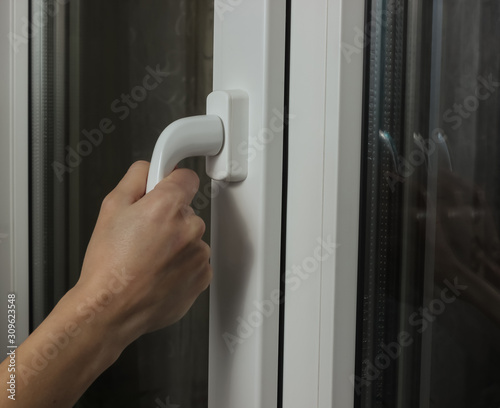 Female hand opens a metal-plastic window for ventilation