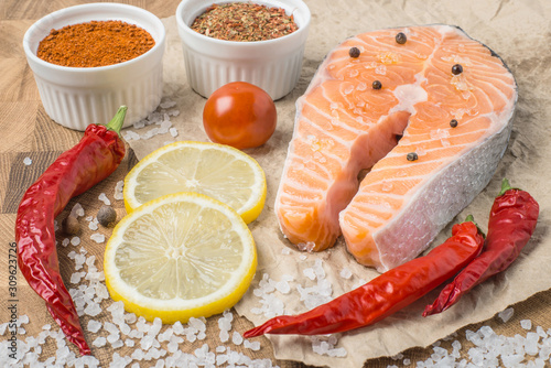 Photography Raw fresh Salmon fillet steak slices with lemon, sol, tomato and ingredients for cooking, condiment