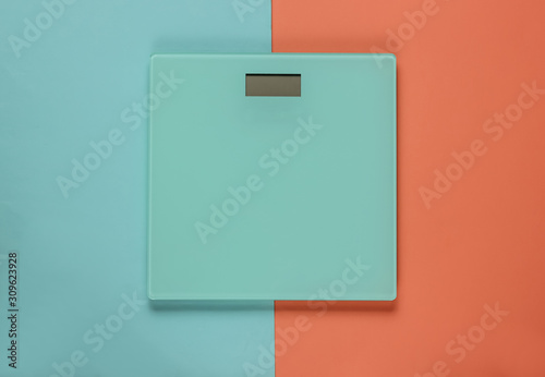 Floor scales on a blue-pink pastel background. The concept of losing weight. Studio shot. Top view