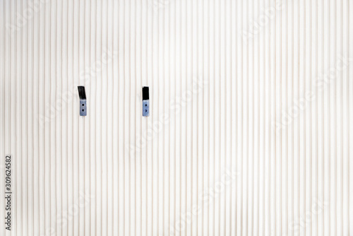 White wall of wooden slats with two hangers, planks pattern background, texture of wood lath wall