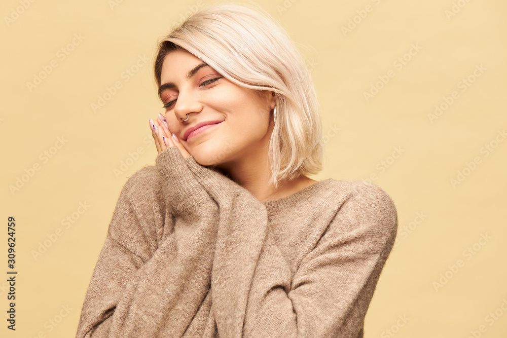 Portrait of sleepy tired young blonde woman with nose ring placing head on hands pressed together and keeping eyes closed, having nap or sleeping, smiling happily. Sleep, bedding and fatigue concept Portrait of sleepy tired young blonde woman with nose ring placing head on hands pressed together and keeping eyes closed, having nap or sleeping, smiling happily. Sleep, bedding and fatigue concept