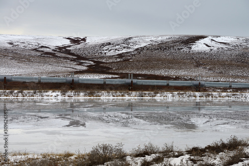 Alyeska elevated Trans Alaska crude oil pipeline passing hills and pond north of the Brooks Range mountains photo