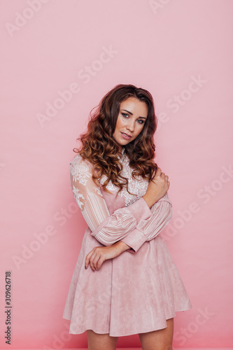 Portrait of a beautiful fashionable woman with hair curls in a pink dress