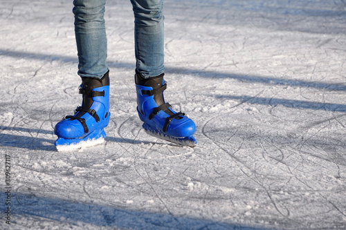 Bright Blue plastic skates in the background of scratched ice in a Sunny day. entertainment in the winter season, active sports. legs of a man in blue skates rides on an ice rink.