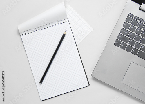 Minimalistic business concept. Laptop, notebook with pencil on white background. Top view