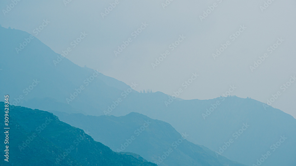 silhouettes of mountains in blue haze. Outline of gentle hills in the valley