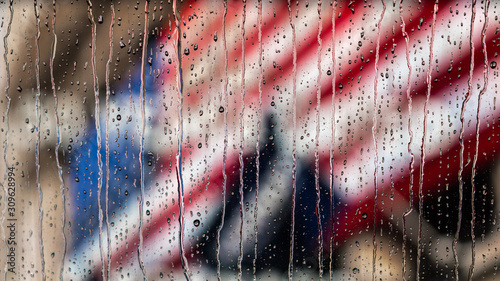 Φωτογραφία American Flag behind rain streaked glass