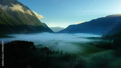 Morning mist over the valley among the mountains in the sunlight. Fog and Beautiful nature of Norway aerial footage.