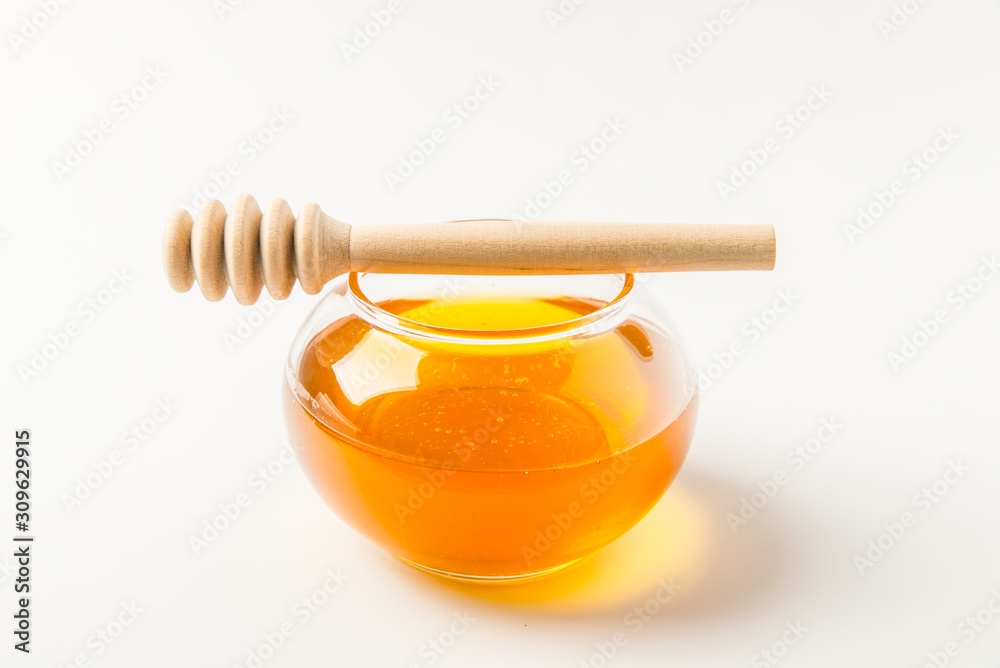 Glass jar of honey with honey dipper isolated on a white background with space for text Glass jar of honey with honey dipper isolated on a white background with space for text