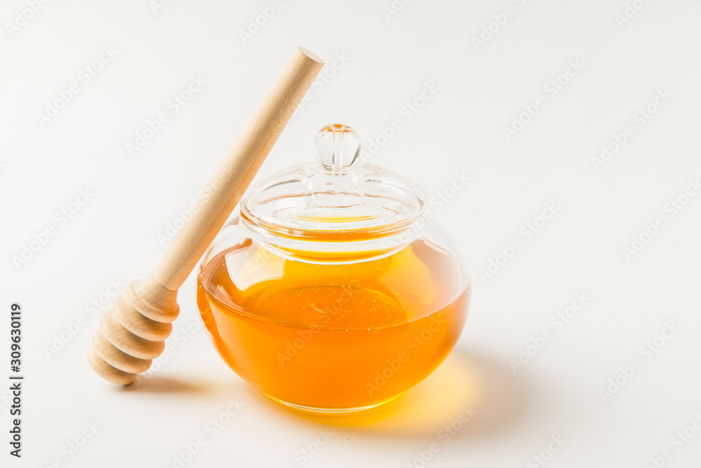 Glass jar of honey with honey dipper isolated on a white background with space for text Glass jar of honey with honey dipper isolated on a white background with space for text