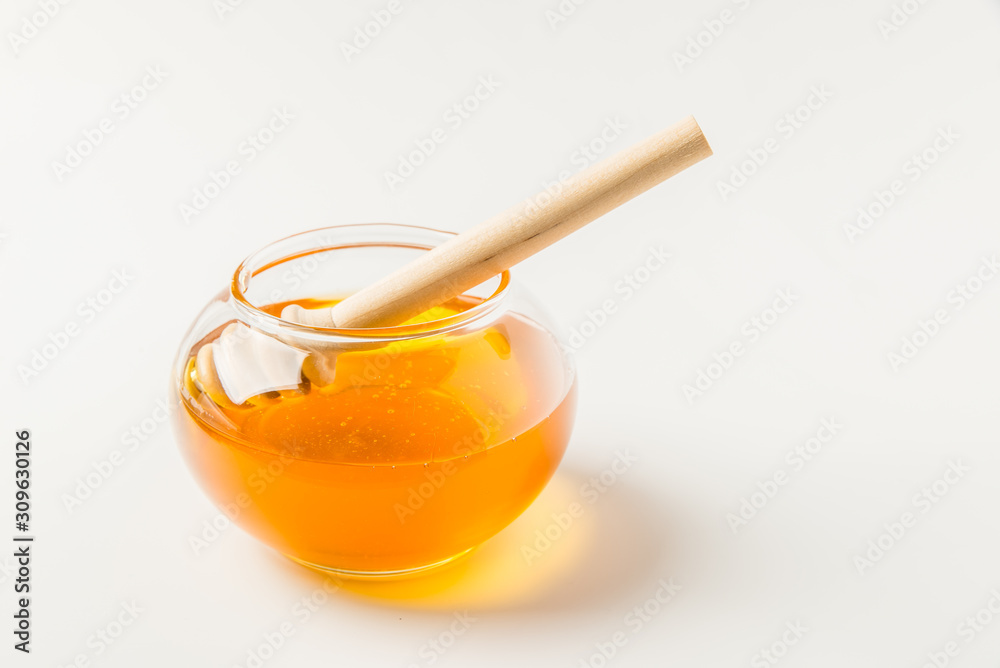 Glass jar of honey with honey dipper isolated on a white background with space for text Glass jar of honey with honey dipper isolated on a white background with space for text
