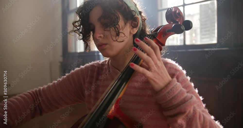 Young woman practicing cello in class