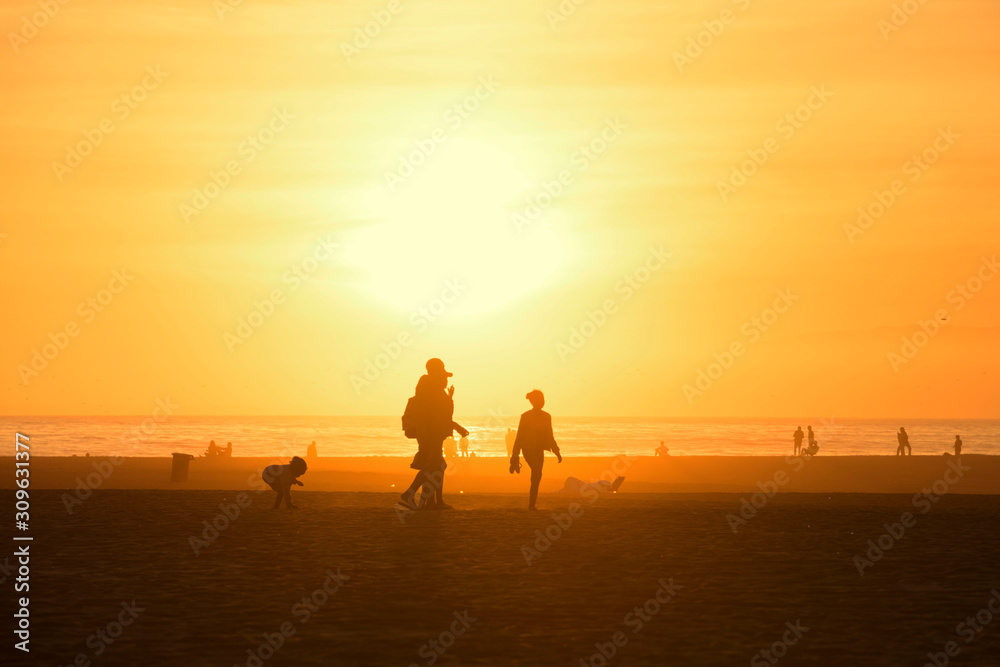 Silhouette background image of people enjoy people walking on the beach in colorful sunset over sky, Santa Monica California, USA.
