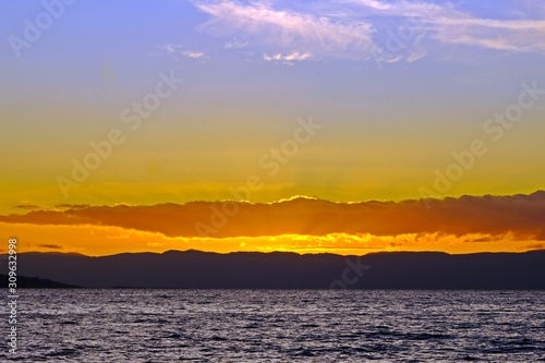 Gorgeous view of sunset on Lake Geneva with golden sun rays spreading from behind the clouds, Vevey, Switzerland.