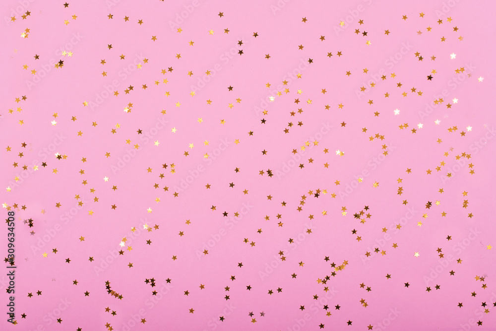 Little gold stars on pastel pink background Festive holiday background. Celebration concept. Top view,