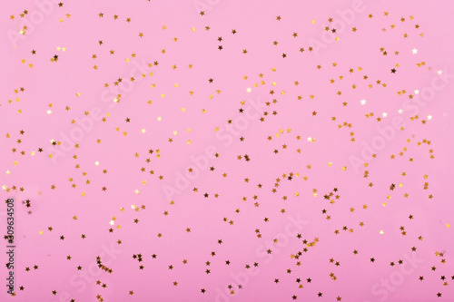 Little gold stars on pastel pink background Festive holiday background. Celebration concept. Top view,