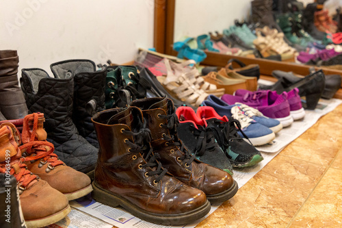 A lot of different used old shoes are laid out on the floor in the hallway. Storage Organization Concept.