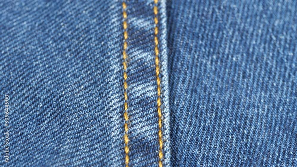 Seam on denim jeans, tracking macro. Denim textile texture, close up low angle. Slider shot. 4K 422 10 bit Seam on denim jeans, tracking macro. Denim textile texture, close up low angle. Slider shot. 4K 422 10 bit