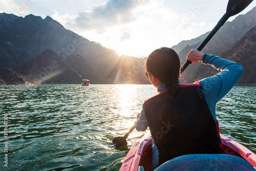 Woman kayaking in Hatta lake in Dubai at sunset photo