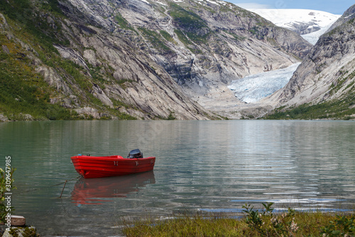 Landscape with red boat under mountains with glacier