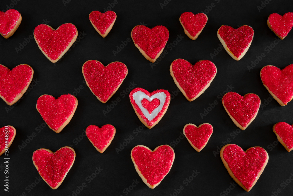 Red and white heart shaped cookies on black background, distinction concept, love symbol, valentine's day pattern