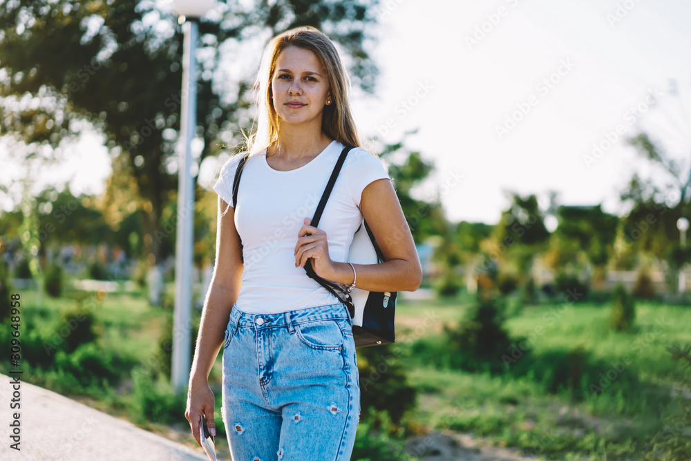 Woman trendy style street fashion, attractive caucasian hipster girl casual dressed strolling in spring city , portrait of gorgeous woman standing outdoors while waiting friend and looking at camera