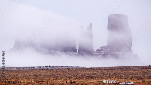 Fog overwhelms Stagecoach, Bear and Rabbit, and Castle Rock at Monument Valley Navajo Tribal Park as seen from the Park access road photo