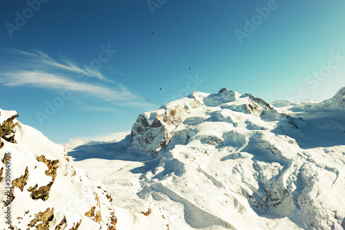 View of snow-capped mountains  with blue sky and a little cloud  black birds flying over the mountain peak.