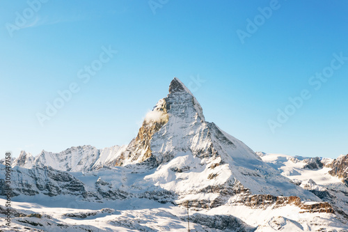 Panorama of the Matterhorn mountain range  covered with fresh snow  and blue sky in the cloudless background. Christmas season  winter and ski slopes on the Swiss Alps.