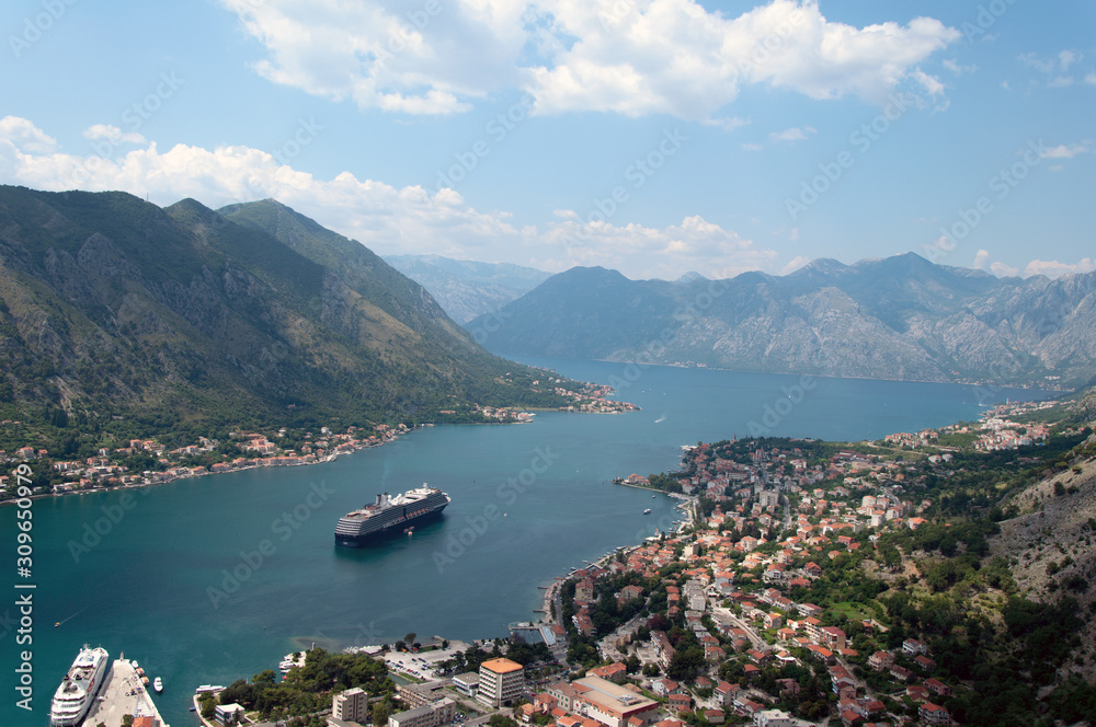 Landscape from the mountains to the bay in the Adriatic Sea. Panorama of the old town on the shore with a cruise ship at sea.