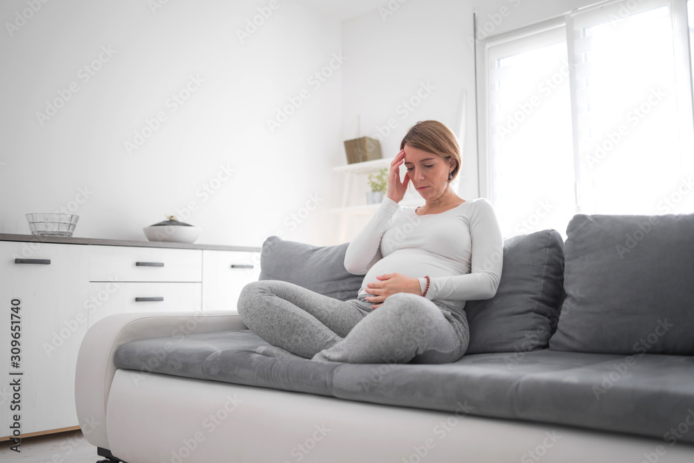 Pregnant tired exhausted woman with stomach and head issues at home on a couch, being sick. Pregnant tired exhausted woman with stomach and head issues at home on a couch, being sick.