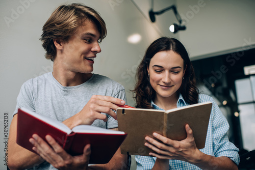 Cheerful Caucasian bloggers laughing during cooperation on information enjoying planning time togetherness, happy hipster guys with textbook for education doing homework tasks while learning