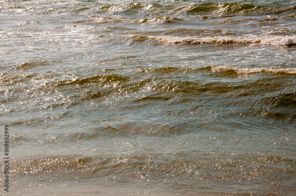 Black Sea. Water with waves. Mainly cloudy weather and sun rays. Blue and grey clouds. Before rain. Sand coast