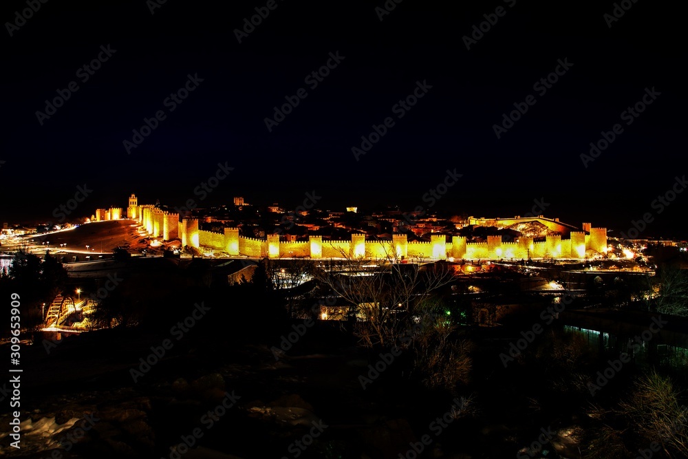 Ávila al anochecer con su muralla medieval iluminada (España).