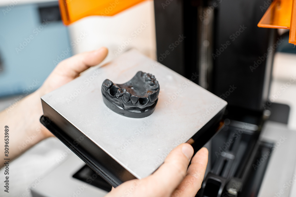 Dental technician removing jaw model from a 3d printer at the laboratory, modeling frame for implant production Dental technician removing jaw model from a 3d printer at the laboratory, modeling frame for implant production