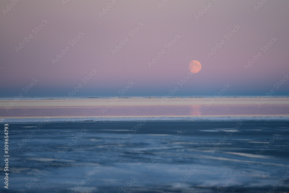 Red Moon rising over pink sky of the Beaufort Sea at Kaktovik Alaska