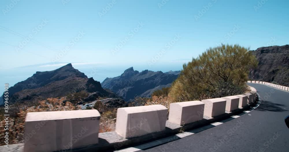 Driving a car on bluff dangerous highway in the mountains landscape. Excting road travel near Masca gorge on Tenerife in sunny summer season. Driving a car on bluff dangerous highway in the mountains landscape. Excting road travel near Masca gorge on Tenerife in sunny summer season.