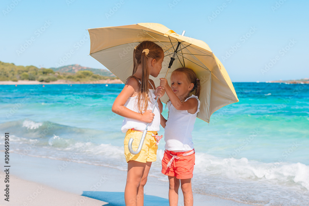 Adorable little girls have fun together on white tropical beach