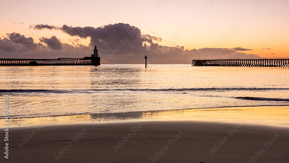 View of Blyth Harbour Piers, Blyth on the coast of Northumberland, England, UK. At sunrise on a winter morning.
