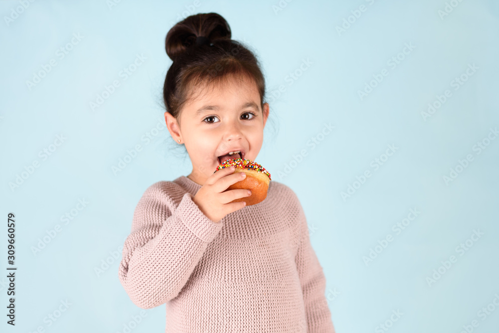 Little happy cute girl eating donut on blue background. Little happy cute girl eating donut on blue background.