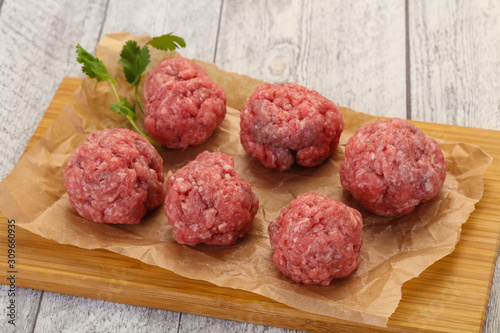 Raw meatball over wooden background