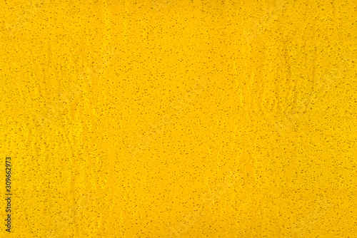 Real texture of yellow, rough material with small holes, illuminated with light.