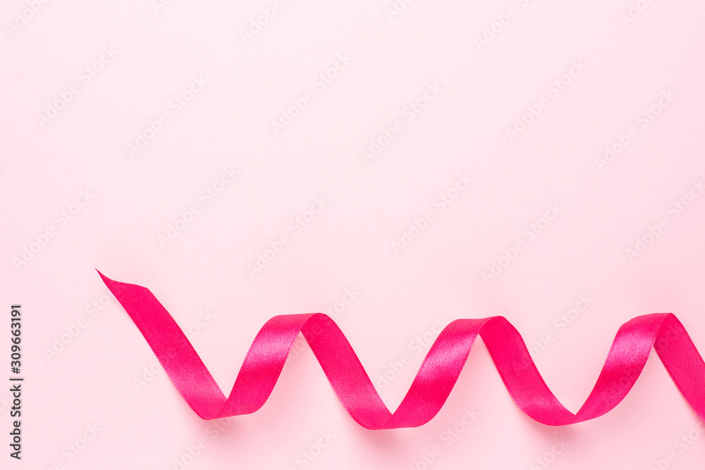 Gift ribbon fuchsia color on pink background. Minimalistic composition for the holidays.