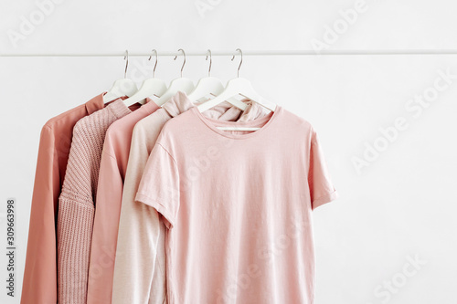 Feminine clothes in pastel pink color on hanger on white background. Spring cleaning home wardrobe. Minimal fashion concept. photo