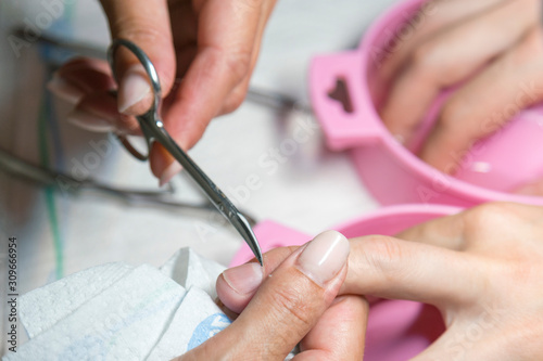 Woman hands receiving manicure and nail care procedure. Close up concept. Manicurist pushing cuticles on female s nails. female nail manicure processing