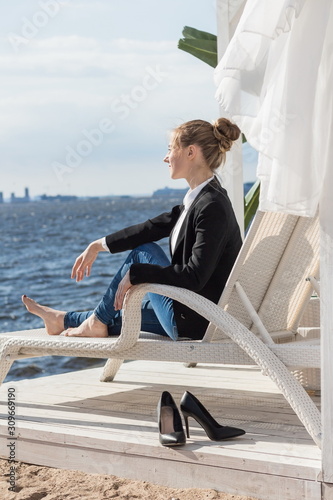 young blond caucasian business woman sitting and relax at terrace in seaside restaurant while lunch in summer sunny day